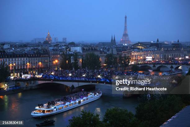 Spectators look on as athletes from Team France pass by on a boat on the River Seine during the opening ceremony of the Olympic Games Paris 2024 on...