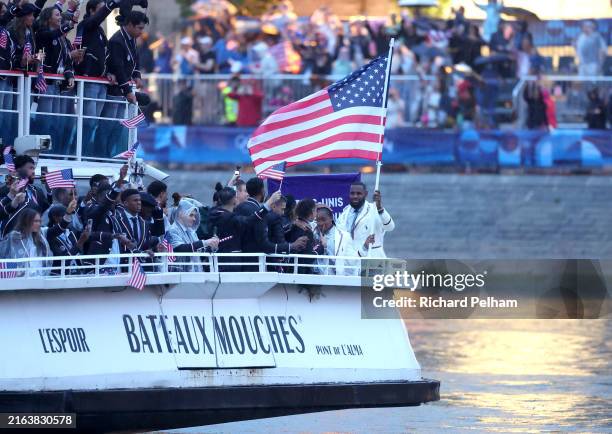 Coco Gauff and LeBron James, Flagbearers of Team United States, are seen on a boat waving their flag along the River Seine during the opening...