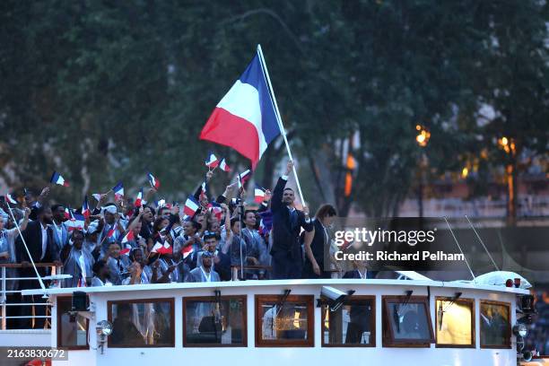 Florent Manaudou and Melina Robert-Michon, Flagbearers of Team France, are seen on a boat waving their flag along the River Seine during the opening...