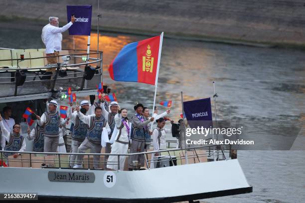 Ser-Od Bat-Ochir, Flagbearer of Team Mongolia, waves the flag on the athletes' parade team boat along the River Seine during the opening ceremony of...