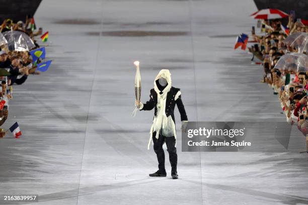 Mysterious Torchbearer holds the Olympic Torch during the opening ceremony of the Olympic Games Paris 2024 on July 26, 2024 in Paris, France.