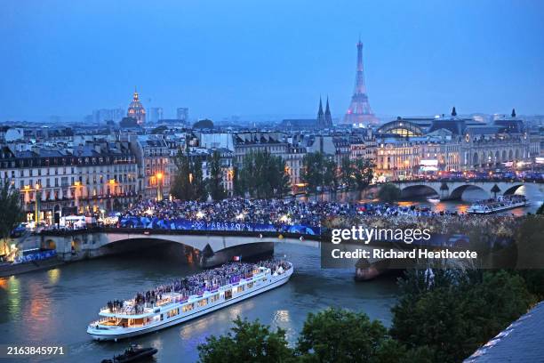 Spectators look on as athletes from Team France pass by on a boat on the River Seine during the opening ceremony of the Olympic Games Paris 2024 on...