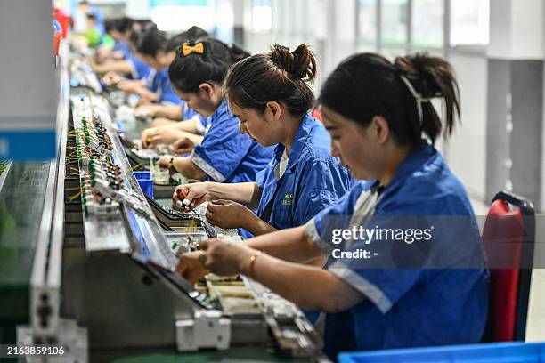 Employees work on a circuit breaker production line at a factory of an electronics company in Fuyang, in China's eastern Anhui province on July 30,...