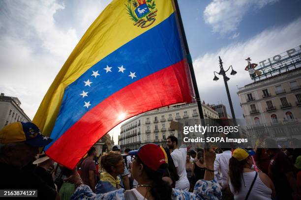 Protester holds a Venezuelan flag, during a demonstration in Puerta del Sol in the center of Madrid. The Venezuelan community residing in Madrid...