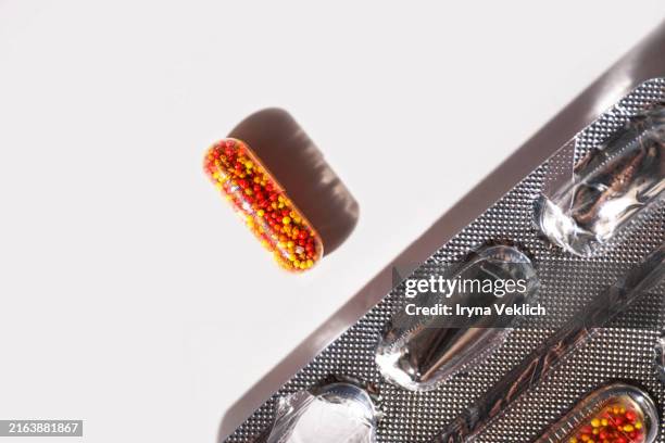 transparent capsules with medicine in shape of colorful balls with iron, vitamin b, vitamin c, folic acid, zinc on a white background with shadow. - vitamin-b12 stock-fotos und bilder