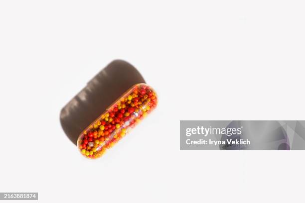 transparent capsule with medicine in shape of colorful balls with iron, vitamin b, vitamin c, folic acid, zinc on a white background with shadow. - vitamin-b-1 stock pictures, royalty-free photos & images