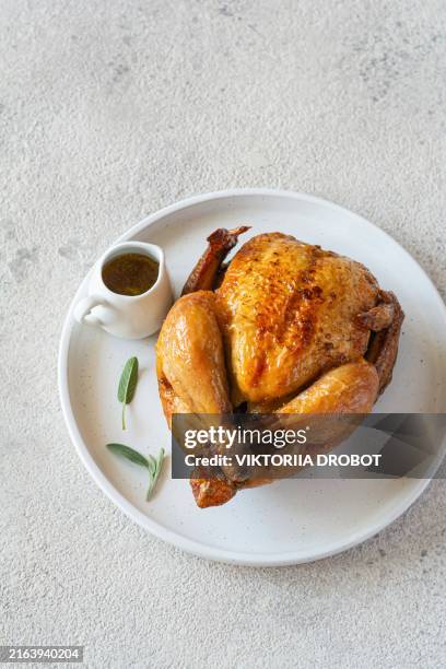 baked chicken (small turkey) with sage for thanksgiving on a light background. festive food. - entero fotografías e imágenes de stock
