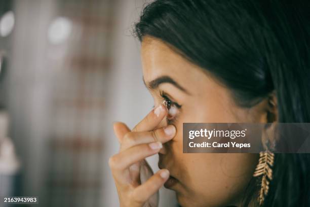 young woman putting contact lens at home - contact lens stock pictures, royalty-free photos & images