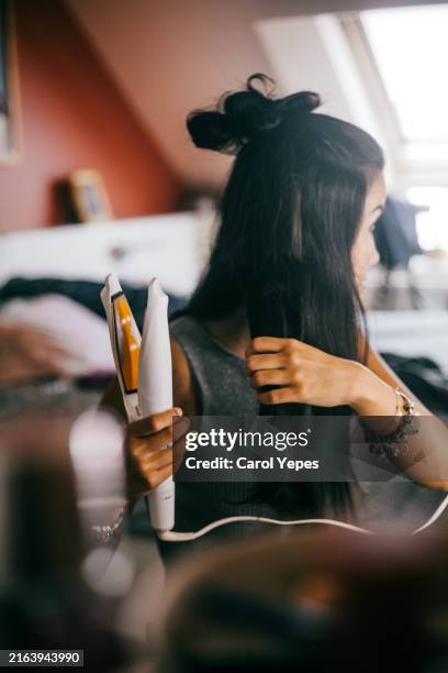 young woman using curl tongs in vanity mirror - lockenstab stock-fotos und bilder