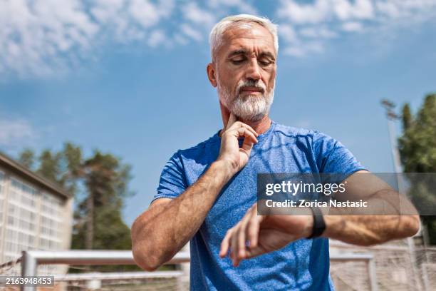 atleta senior tomando el pulso en el estadio - tomando el pulso fotografías e imágenes de stock