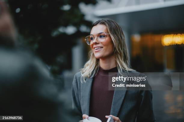 selbstbewusste geschäftsfrau, die mit einem lächeln durch die straße der stadt geht - junge frau allein stock-fotos und bilder