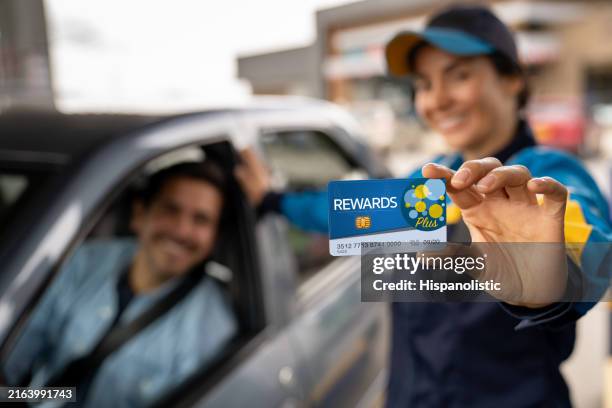 gas station attendant holding a loyalty card - loyalty program stock pictures, royalty-free photos & images