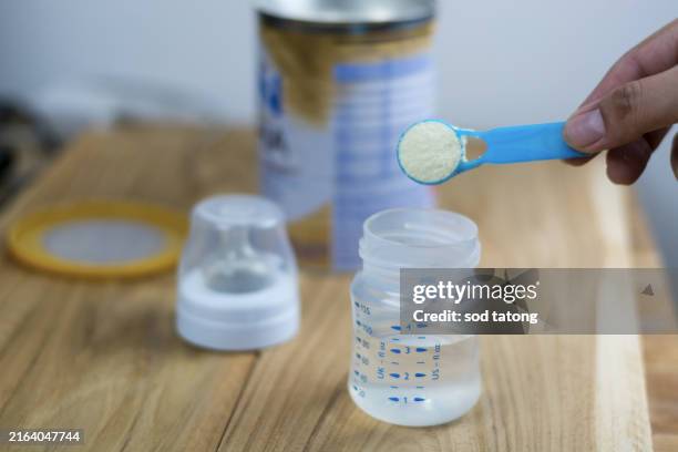 powder milk and blue spoon on light background close-up. milk powder for baby in measuring spoon on can. powdered milk with spoon for baby. baby milk formula and baby bottles - milchpulver stock-fotos und bilder