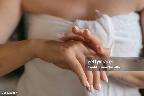 a woman applies moisturizer or anti-aging cream to the skin of her hands - anti age stock-fotos und bilder