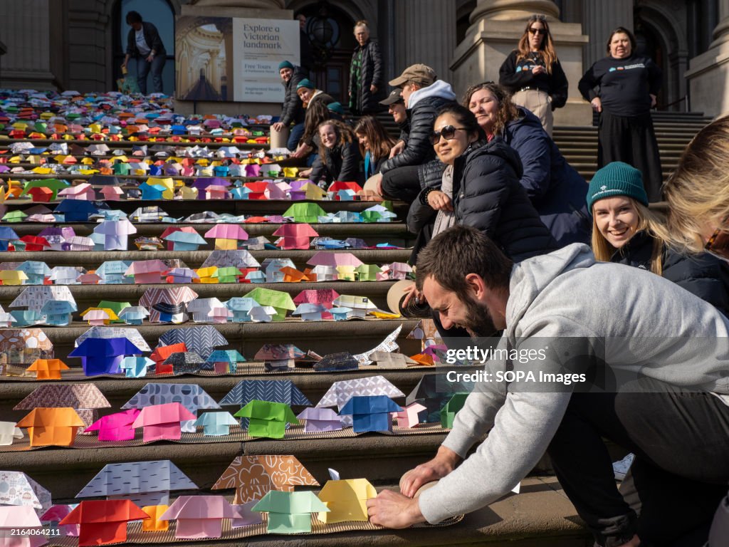 Volunteers roll up the rows of origami houses after the...