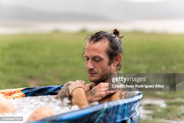 young man taking ice bath outdoors for muscle recovery after workout - taking a bath stock pictures, royalty-free photos & images