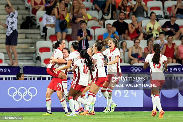 Canada's defender Vanessa Gilles celebrates with teammates after scoring her team's first goal during the women's group A football match between...