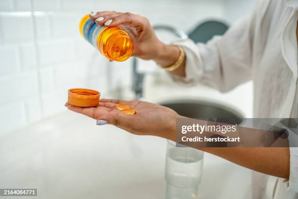 close-up of a woman's hand pouring fish oil from a bottle - vitamine d stockfoto's en -beelden