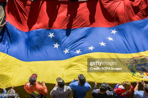 Supporters of Venezuelan President Nicolas Maduro carry a large Venezuelan flag during a march in Caracas to support the re-elected president....