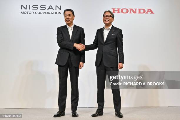 Makoto Uchida , president and CEO of Japanese auto maker Nissan, shakes hands with Toshihiro Mibe , director, president and representative executive...
