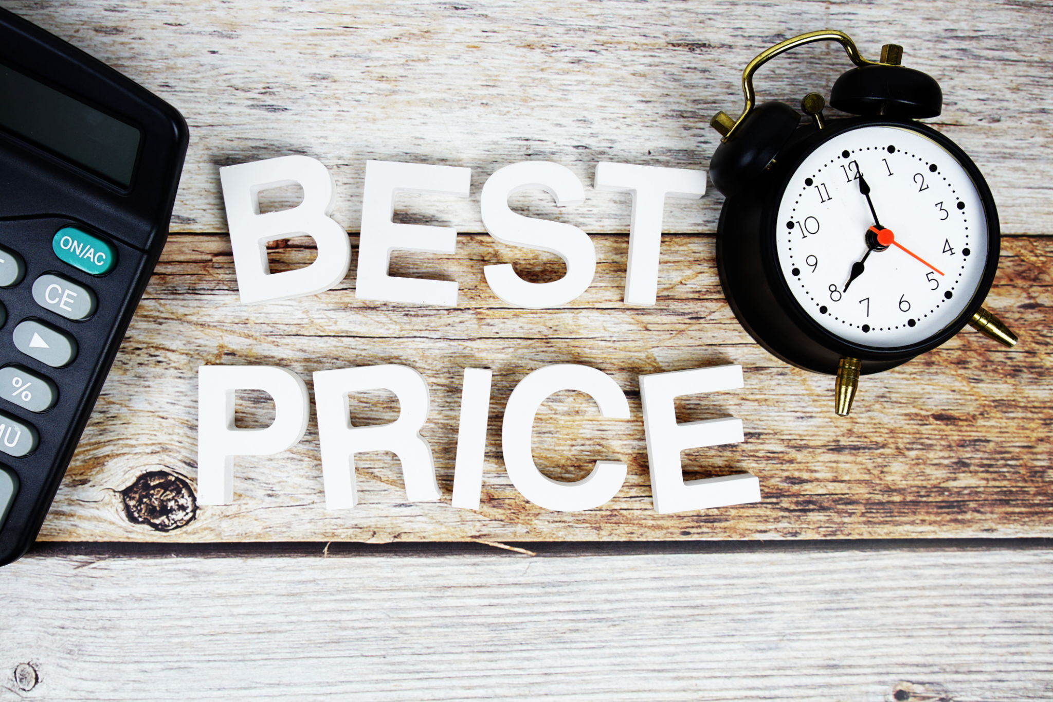 Best Price with alarm clock and calculator alphabet letters on wooden background Best Price with alarm clock and calculator alphabet letters on wooden background