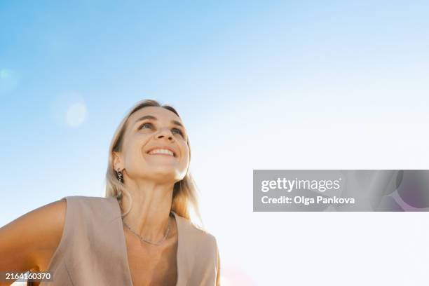 beautiful middle-aged woman looks up against a cloudless sky on a sunny day - inquadratura estrema dal basso foto e immagini stock