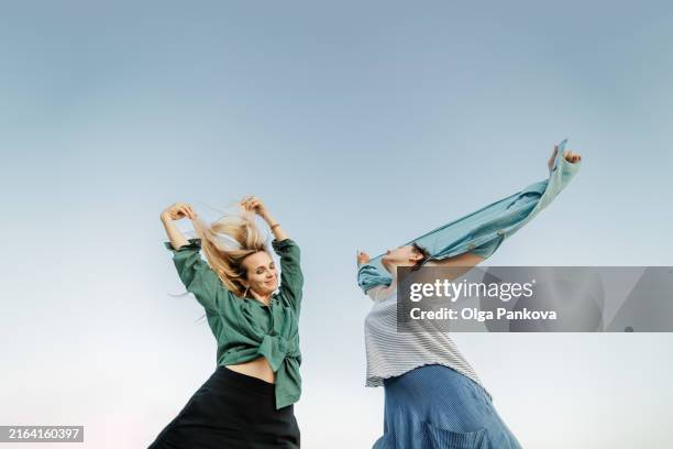 two women enjoy each other's company, have fun and dancing under a cloudless sky. - danseres stockfoto's en -beelden