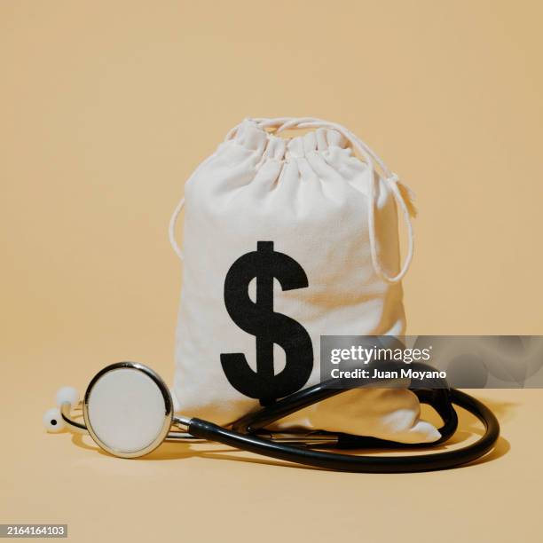 money sack and stethoscope - capitalismo fotografías e imágenes de stock