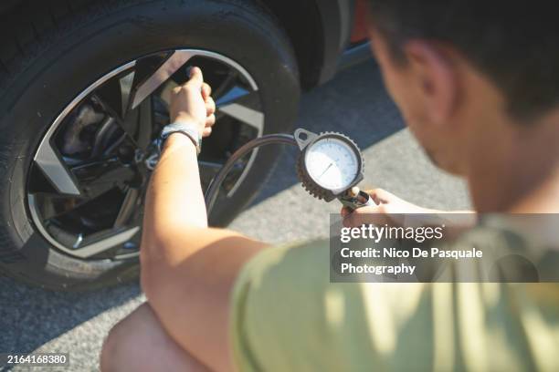 rear view of man inflating tires of his car - swing low stock pictures, royalty-free photos & images