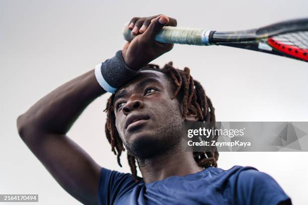 the tennis player is wiping sweat from their forehead with their wrist. - sweat band stock pictures, royalty-free photos & images