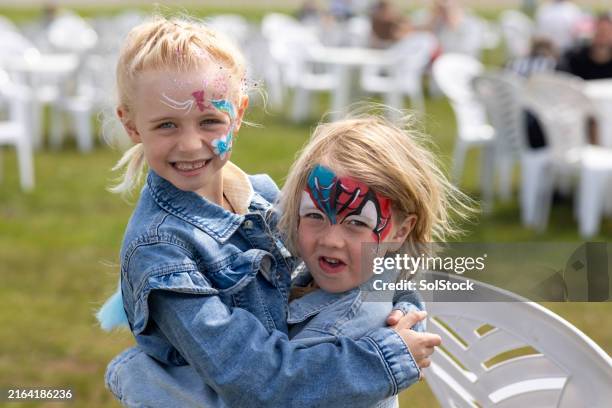 amor entre hermanos en un día divertido - pintura de cara fotografías e imágenes de stock