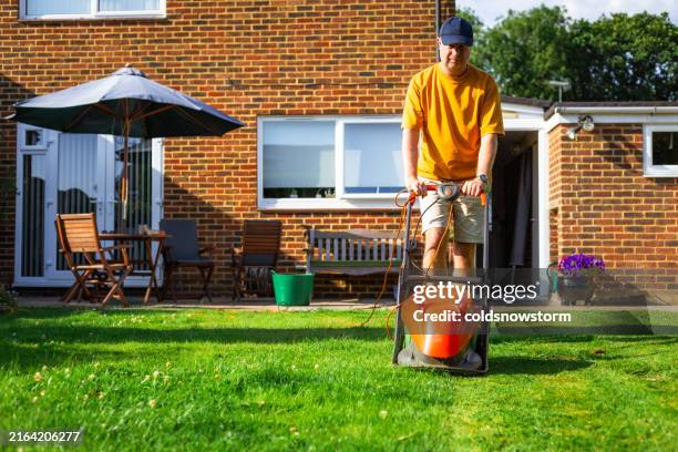 mid adult male home owner mowing lawn on summer evening - semi detached house stock pictures, royalty-free photos & images