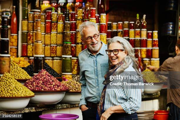 medium shot senior couple at olive stand in the medina of marrakech - turismo esperienziale foto e immagini stock