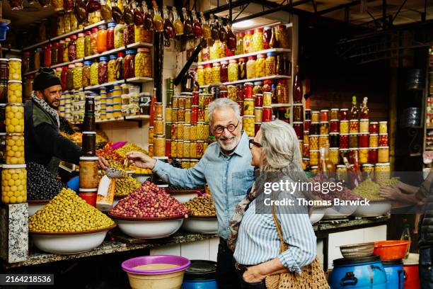 medium wide shot couple sampling olives in the medina of marrakech - marokko stock-fotos und bilder