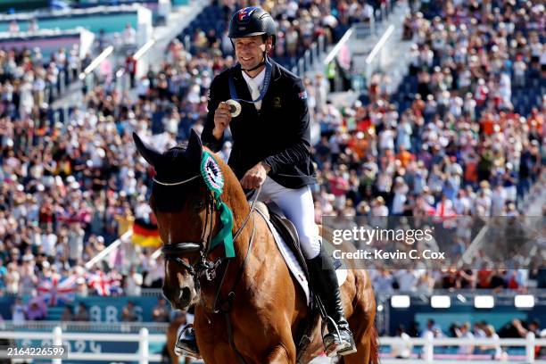 Silver medalist Christopher Burton with horse Shadow Man of Team Australia celebrate during a lap of honour after the medal ceremony for the Eventing...
