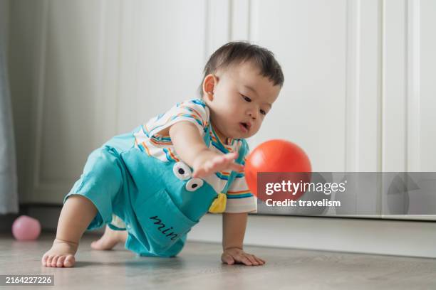 cute asian baby boy in casual cloth crawling on floor and playing with his favorite ball toy at apartment smile and learning with toy at home on ground for games, daycare and fun creativity - sphere stock pictures, royalty-free photos & images