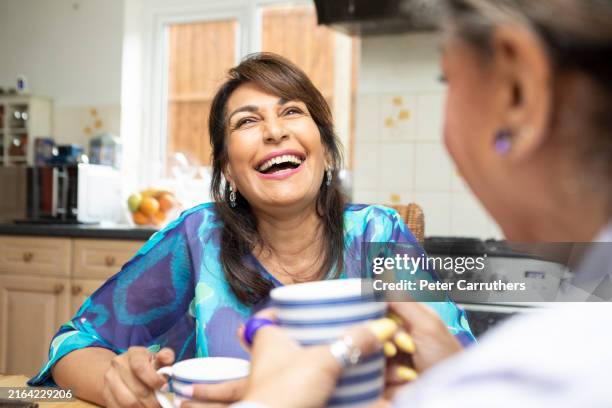 allegre donne mature che fanno una pausa caffè insieme in una cucina - solo donne mature foto e immagini stock