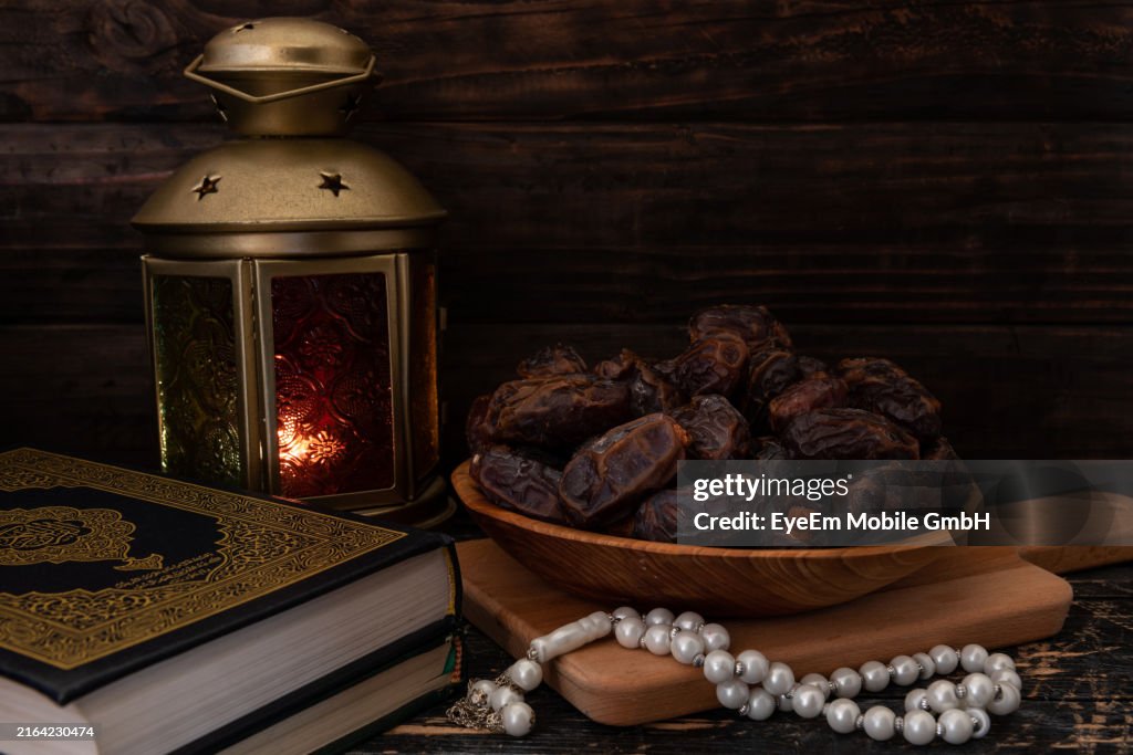 Dried Dates Or Kurma In A Wooden Plate, Rosary Beads, Holy Quran And A Lantern.