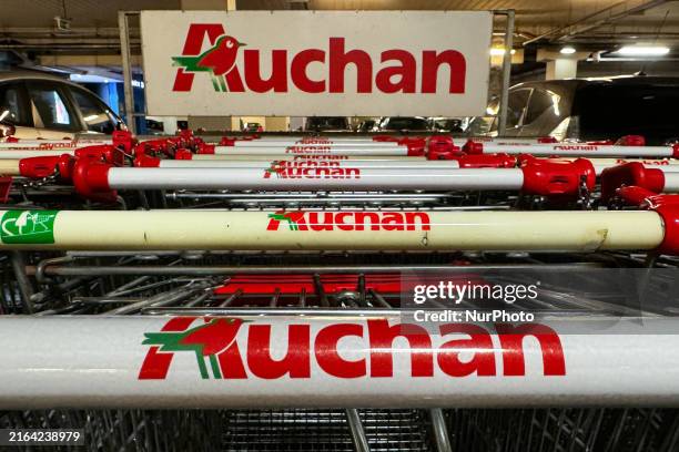 Auchan logos are seen on shopping trolleys near the supermarket in Krakow, Poland on August 1, 2024.