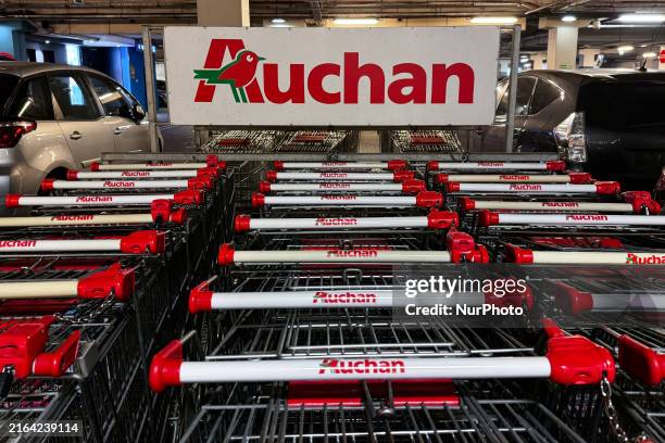 Auchan logos are seen on shopping trolleys near the supermarket in Krakow, Poland on August 1, 2024.