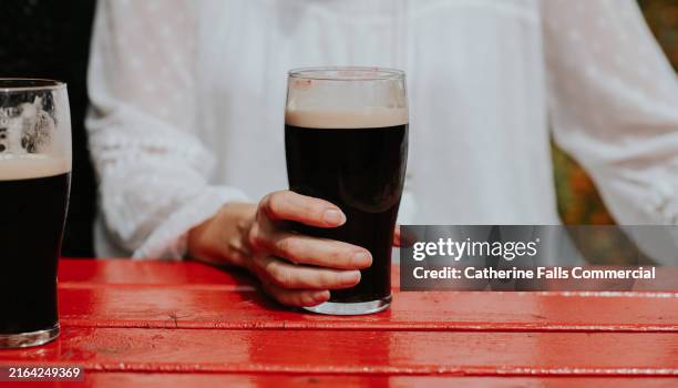 close-up of a woman holding a pint of stout - biergarten stock-fotos und bilder