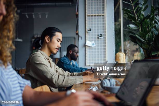 people working and socializing in a cozy cafeteria setting - digital nomad stock pictures, royalty-free photos & images