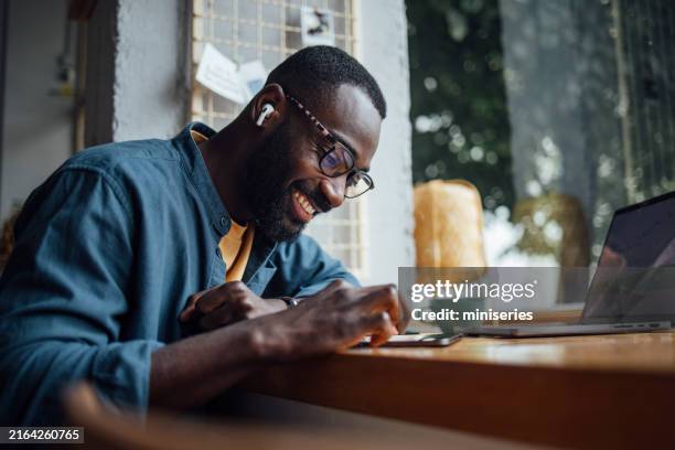 hombre trabajando en tableta en acogedor café con computadora portátil - masculinidad moderna fotografías e imágenes de stock