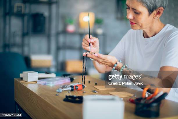 senior woman making jewelry in a home workshop - bead stock pictures, royalty-free photos & images