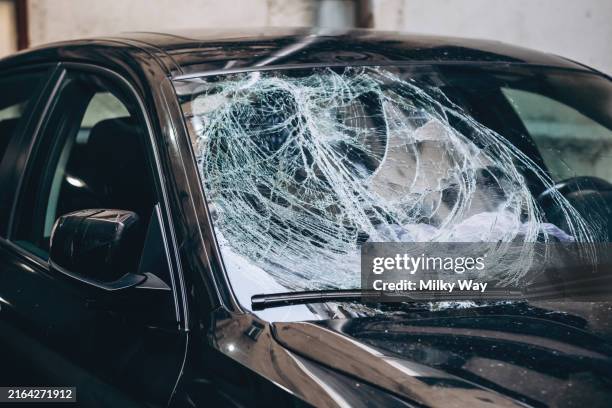 close-up of a black car with a shattered windshield, showing damage. - siniestro fotografías e imágenes de stock