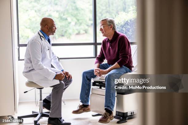 male doctor talking with senior man in exam room - doctor stethoscope patient whole body stock pictures, royalty-free photos & images