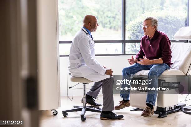 male doctor talking with senior man in exam room - doctor's surgery stock pictures, royalty-free photos & images