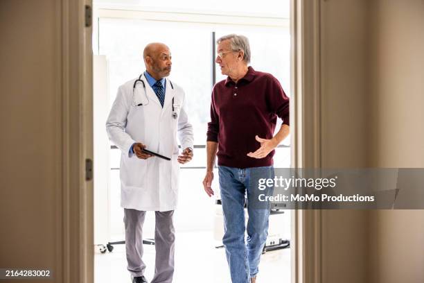male doctor talking with senior man in exam room - doctor stethoscope patient whole body stock pictures, royalty-free photos & images