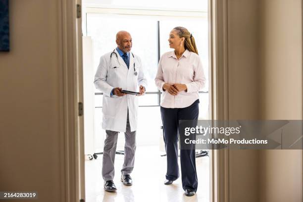 male doctor talking with female patient in exam room - doctor stethoscope patient whole body stock pictures, royalty-free photos & images