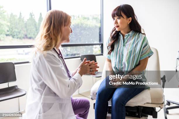 female doctor talking with young woman in exam room - kontroll bildbanksfoton och bilder